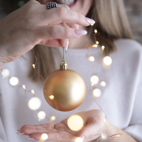 mani di ragazza e pallina di natale con lucine