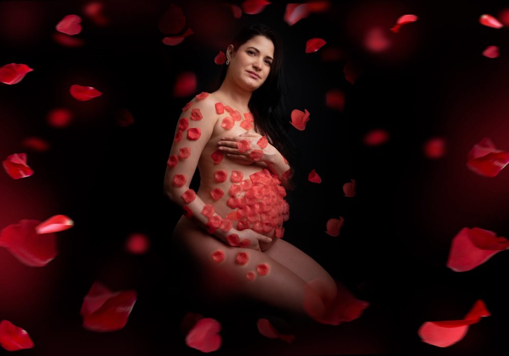 servizio fotografico gravidanza con petali rossi su fondale nero